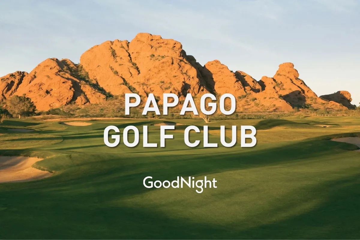 A wide view of a manicured golf course surrounded by striking rock formations and an open sky. Golfers are visible enjoying a round, with lush green fairways blending into the natural desert landscape, evoking Scottsdale's renowned golf culture.